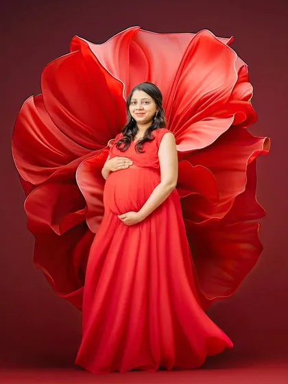 A bold and passionate portrait using a vibrant red gown and fabric art. The color red symbolizes love and life, making it a powerful choice for a dramatic maternity photo.