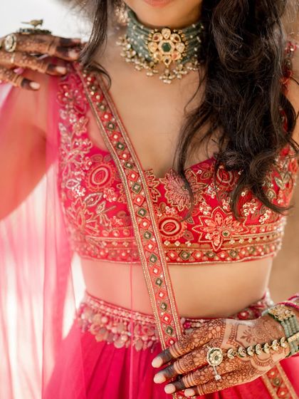 It's all in the details. A close-up of the bride's Sangeet look, showing her statement green choker, intricate blouse embroidery, and beautiful henna-adorned hands.