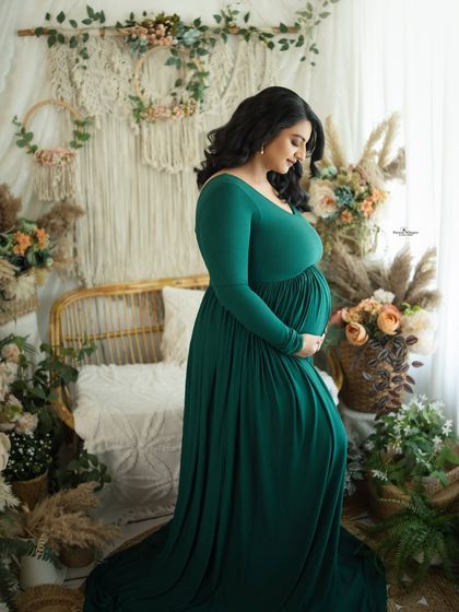 A full-length portrait by the window, using natural light to create a soft and ethereal glow. The green gown looks rich and elegant in this setting.