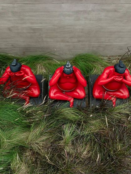 A close-up of the three red sumo wrestler sculptures, an art installation by Hoozinc Studio. These playful figures add a bold and unexpected element to the landscape design.