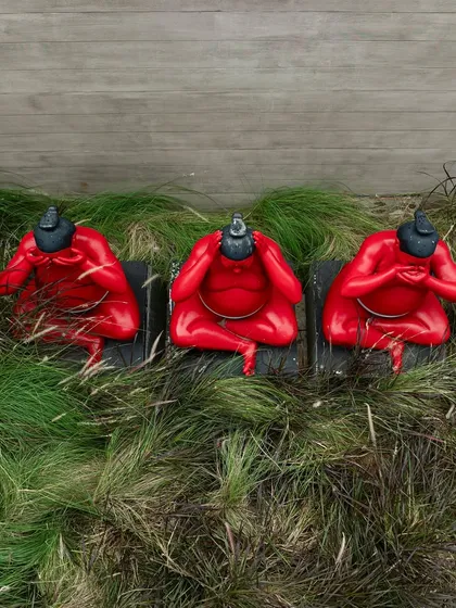 A close-up of the three red sumo wrestler sculptures, an art installation by Hoozinc Studio. These playful figures add a bold and unexpected element to the landscape design.