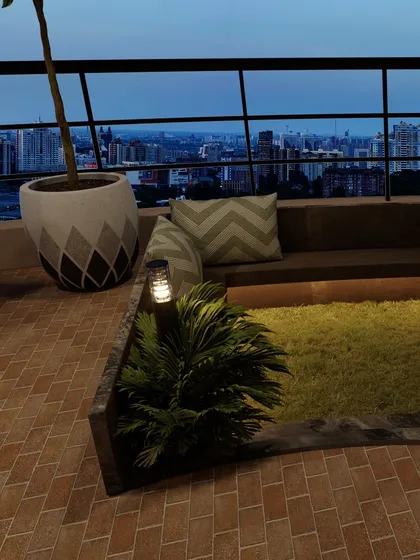 Another view of the built-in seating area at night, where landscape lighting highlights the greenery and creates a warm, inviting glow.