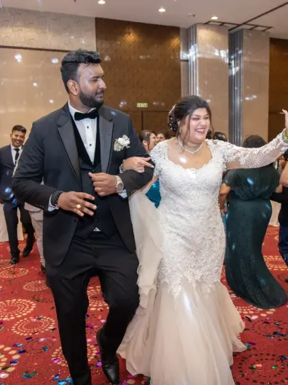 The bride and groom leading the way onto the dance floor. This candid shot captures the movement and excitement as the wedding party gets started.