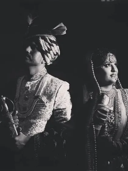 A powerful black and white portrait of the bride and groom in their traditional wedding attire, looking regal and timeless.