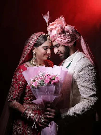 A romantic wedding portrait with dramatic red backlighting, capturing the couple in a loving embrace.