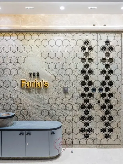 The entrance with the security door closed, showcasing the full fish-scale pattern that flows from the wall onto the door itself. The gold nameplate and modern console complete the luxurious look.