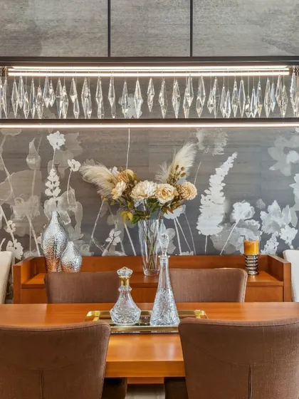 A closer view of the Phillip Jeffries Wildflowers wallpaper, where the detailed floral silhouettes create a dramatic and beautiful backdrop. The design perfectly complements the modern, luxurious dining furniture.