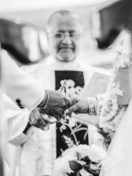 A powerful black and white shot of the ring exchange, framed through the pews. This unique perspective makes the moment feel intimate and sacred.