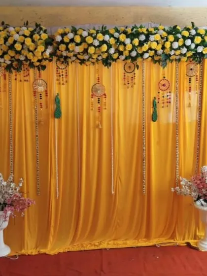A classic and vibrant Haldi ceremony backdrop. We used bright yellow drapes, an overhead floral arrangement of marigolds and white roses, and traditional dreamcatcher hangings to create a beautiful setting for this pre-wedding ritual.