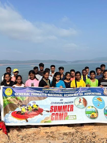 A group of KRIES students proudly holds up the GETHNAA summer camp banner at the Dandeli backwaters.
