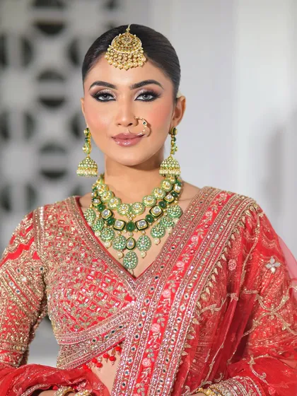 A close-up portrait focusing on the bride's sharp, winged eyeliner and perfectly coordinated green jewelry. This look is for the bride who loves a touch of modern drama.