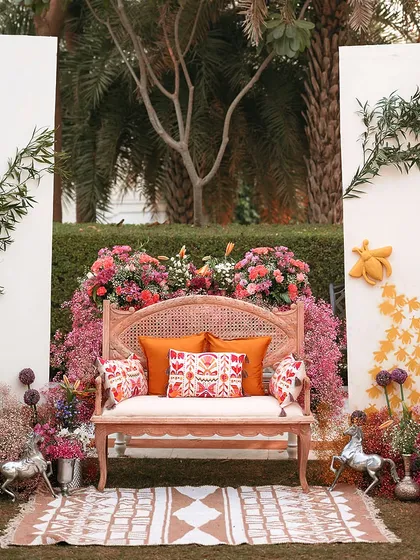 The main seating area for the Haldi ceremony, framed by a wall of vibrant flowers. The design is both grand and intimate, creating a perfect focal point.