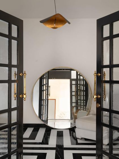 This dramatic entryway from our 'Ebony & Ivory' project uses bold black and white striped marble flooring to create a powerful visual path. The large circular mirror reflects the space, amplifying light and adding a sense of infinite depth.