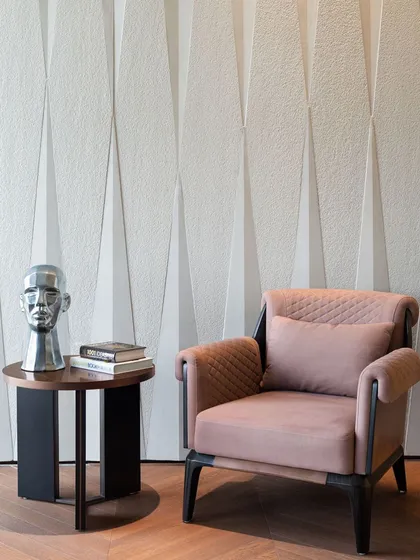 A detail shot from the lounge, where a sculptural stone wall provides a textured backdrop for a comfortable armchair. This demonstrates how a single material can unify different zones within an office.