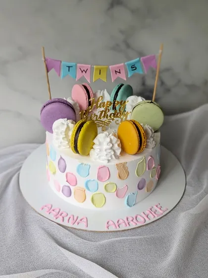 A simple and sweet macaron cake for twins Aarna and Aarohee. The pastel-colored palette knife strokes and colorful macarons make it a cheerful celebration cake.