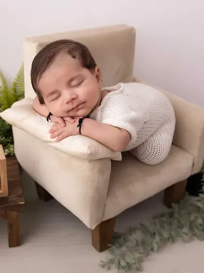 The peaceful, sleepy moments of a newborn are so precious. In my studio, I create a calm and safe space to pose your little one, focusing on capturing their serene innocence and tiny details, like this sweet baby dreaming on a miniature armchair.