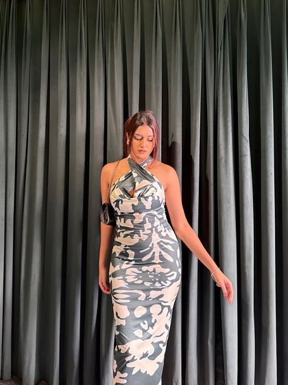 Posing against a simple curtain, which makes the dress's pattern stand out.