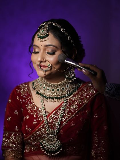 A close-up of the bride getting her makeup touched up. This behind-the-scenes shot captures the final moments of her preparation and her happy anticipation.