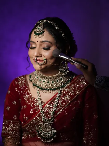 A close-up of the bride getting her makeup touched up. This behind-the-scenes shot captures the final moments of her preparation and her happy anticipation.
