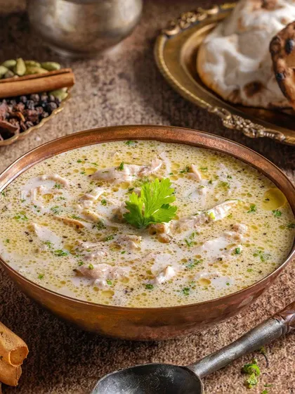 A comforting bowl of Chicken Shorba. The styling for The Mughal House focuses on the creamy texture and subtle spices, presenting it as a warm and inviting soup.