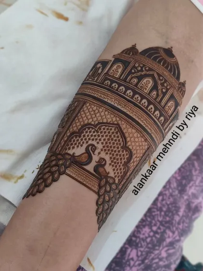 The peacocks are now partially filled, and the design extends down the arm, creating a beautiful narrative piece.