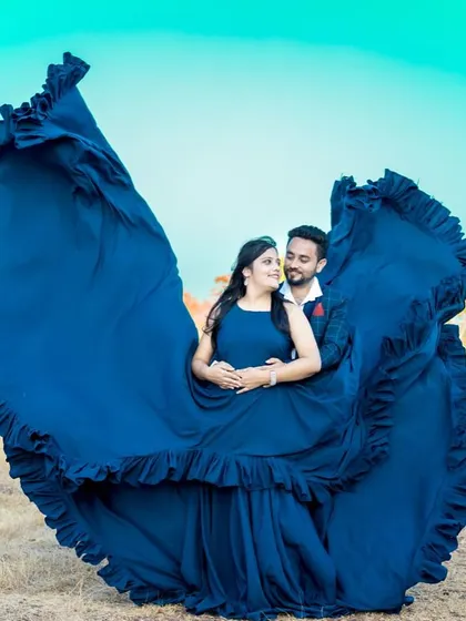A breathtaking "flying gown" shot. The massive trail of this blue dress creates a stunning wing-like effect, perfect for a dramatic pre-wedding photo.