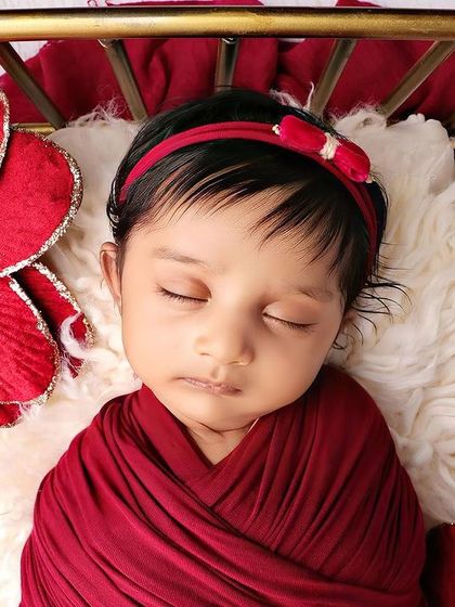 A detailed close-up of the baby's face, showing the texture of the red headband.
