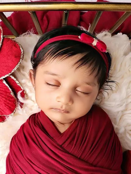 A detailed close-up of the baby's face, showing the texture of the red headband.