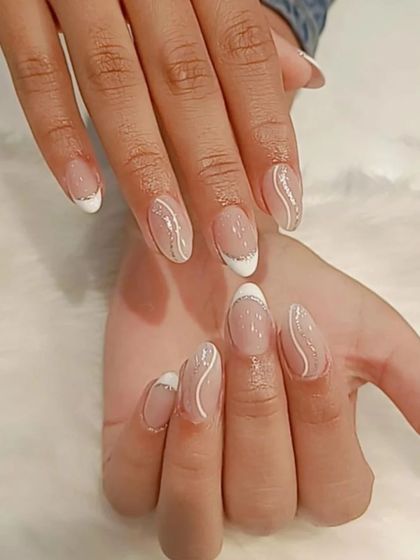 A delicate and elegant design featuring a thin white French tip and subtle, wavy silver glitter lines on almond-shaped nails.