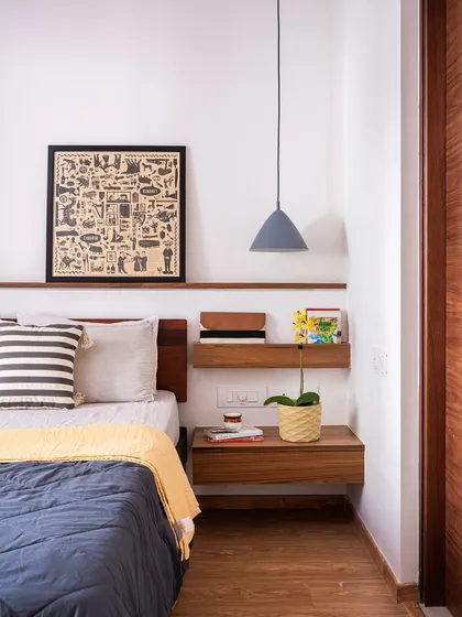 In the 'Footloose' studio apartment, the bedroom corner features a bed with a wooden headboard that extends into a floating bedside table and a display ledge above.
