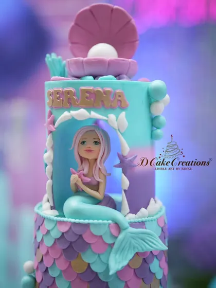A detailed shot of the hand-sculpted mermaid figure, nestled within her coral grotto on the cake.