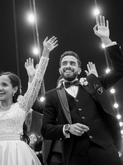 A classic black and white shot capturing the couple's happiness. The string lights in the background add a touch of magic to this timeless moment of celebration.