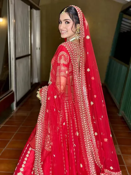 A beautiful shot from the back, showing the full effect of the red lehenga and dupatta. The makeup remains flawless from every angle.