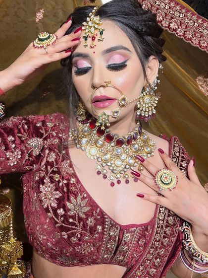 A close-up on the stunning eye makeup and jewelry. The bright pink eyeshadow provides a beautiful contrast to the deep maroon of the lehenga.