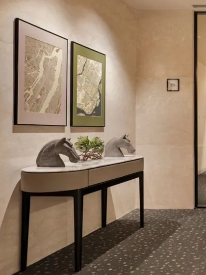 Details matter in creating a cohesive design narrative. This console table in a hallway at the Elevate Clubhouse features elegant horse-head sculptures and framed map artwork, adding a touch of sophistication and personality to a transitional space. The terrazzo-style carpet adds texture and durability.