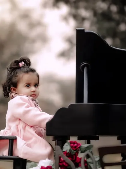 A quiet, thoughtful moment of a little girl in a pink coat playing the piano in a misty park.