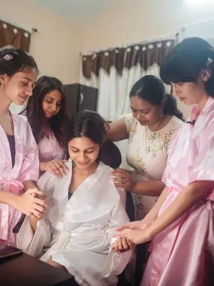The bride surrounded by her bridesmaids in matching robes, sharing a prayer or a moment of quiet support before the ceremony.