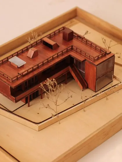 A beautifully crafted wooden model of a Holiday Home project. This model details the facade, roof structure, and relationship to the site, serving as a key presentation tool.