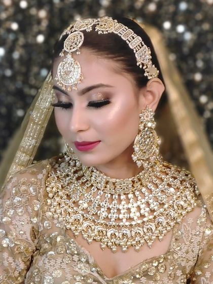 A magnificent, heavy all-gold bridal set. This style is perfect for brides who want a pure royal gold look, featuring a wide choker, large earrings, and a matching matha patti.