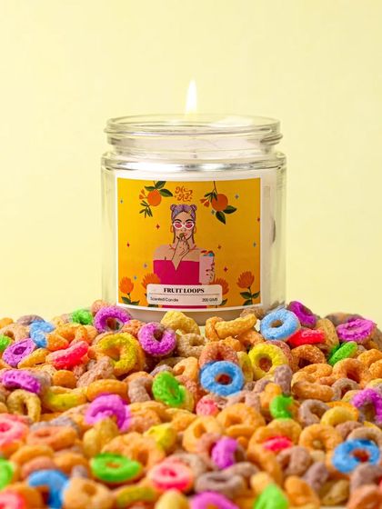 A mountain of colorful fruit loops creates a vibrant and playful bed for this scented candle. The image is an explosion of color and texture, perfectly capturing the candle's whimsical theme.