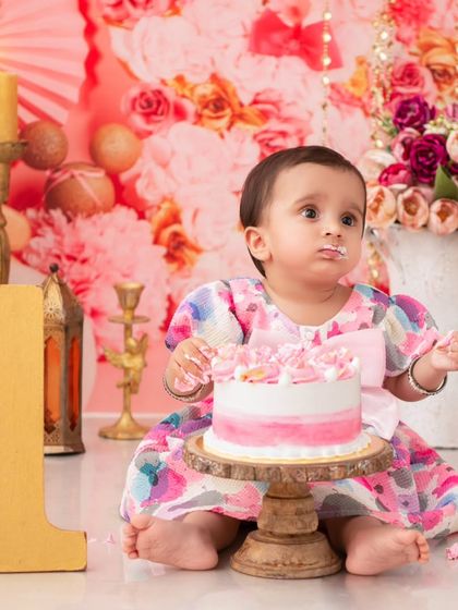 A first birthday cake smash with a beautiful watercolor-themed cake. The soft pinks and floral background create a dreamy and artistic setting.