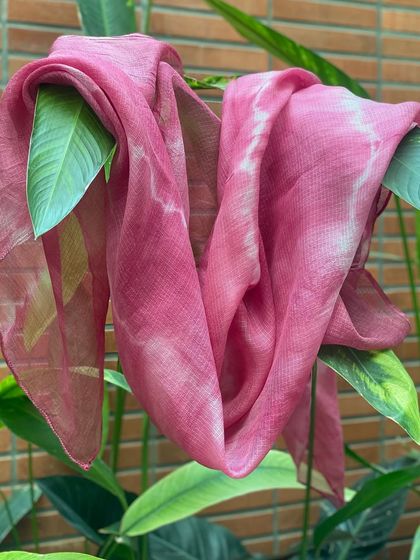 The 'Flamingo' pink Kota silk stole, draped elegantly amongst green leaves. The color combination is just beautiful.