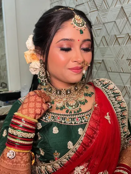 A close-up of Gauri's makeup, featuring shimmery eyeshadow, a traditional nath, and beautiful green stone jewellery.
