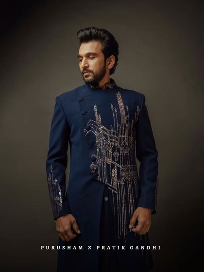 A profile view of Pratik Gandhi in the navy bandhgala. The embroidery is designed to look like a city skyline, a declaration of modern power.