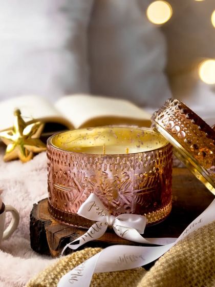 Another angle of the pink candle jar, this time open to show the wax inside. The soft focus background with twinkling lights enhances the dreamy, festive mood of this cozy setup.