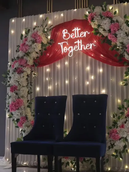 For a modern and romantic ring ceremony, we design backdrops like this one. It features a floral ring, soft drapes with fairy lights, and a custom neon sign like 'Better Together' to make your engagement stage truly personal.