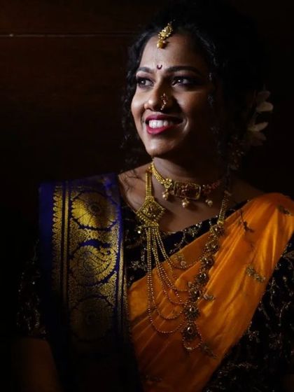A beautifully captured candid moment of a happy bride. The lighting highlights her radiant skin and the rich colors of her yellow and blue saree.