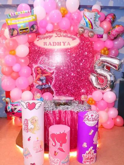 This Barbie-themed cake table is a dream come true, with a glittering backdrop, themed pedestals, and a fantastic balloon arrangement. It's the centerpiece of a perfect party.