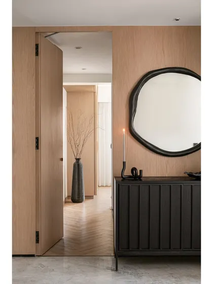A glimpse from the living area into the master bedroom corridor, showing how natural oak doors and herringbone flooring create a warm and continuous flow throughout the home.