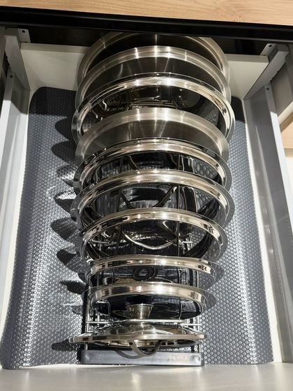 A unique vertical storage solution for steel lids and plates. This pull-out rack is an excellent use of a narrow cabinet space, keeping items secure and accessible.